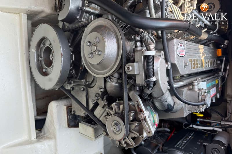 Een close-up van een scheepsmotor met riemen, poelies en diverse leidingen, met "Yanmar Diesel" leesbaar op de motor.
