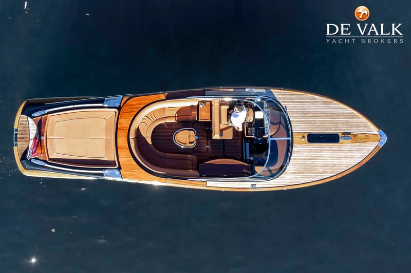 Een bovenaanzicht van een houten motorboot met bruine bekleding, drijvend op donkerblauw water. — Riva Aquariva Cento