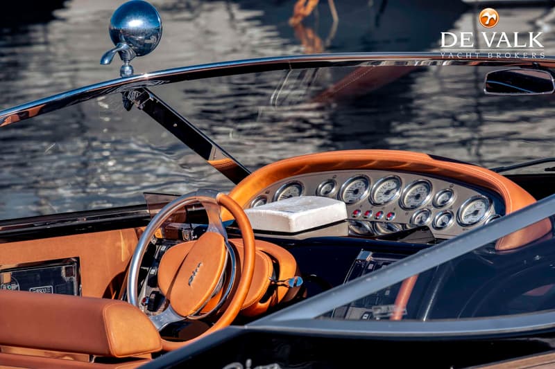 De foto toont het stuur en dashboard van een boot, met een bruinleren afwerking en diverse meters. — Riva Aquariva Cento