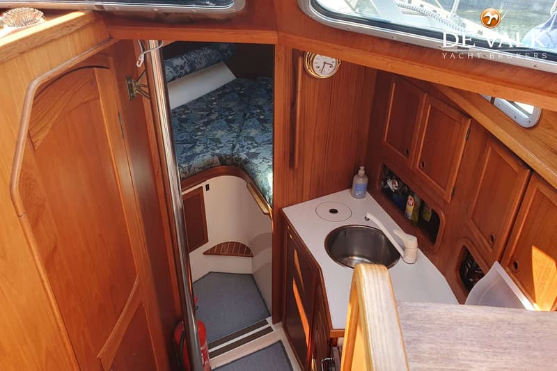 De foto toont een interieur van een boot met een kombuis, een slaapgedeelte en houten afwerkingen. — Nauticat 32