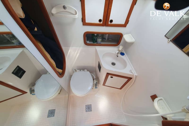 Een badkamer met een toilet, wastafel, spiegel, opbergkastjes en een douchekop.