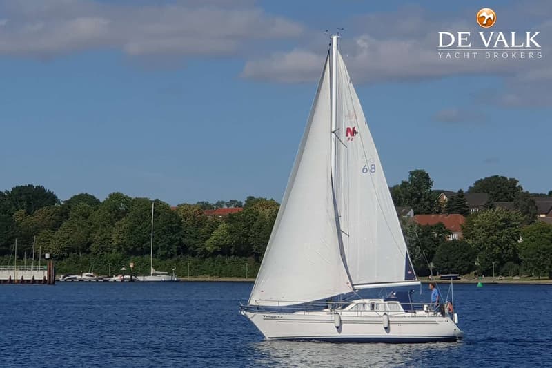 Een witte zeilboot met de naam "Tongji-Er" vaart op blauw water onder een deels bewolkte hemel. — Nauticat 32