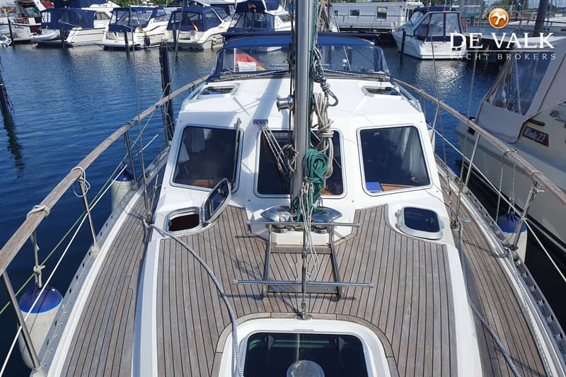 Een bovenaanzicht van het dek van een zeilboot met een houten dek, omringd door andere boten in een haven. — Nauticat 32