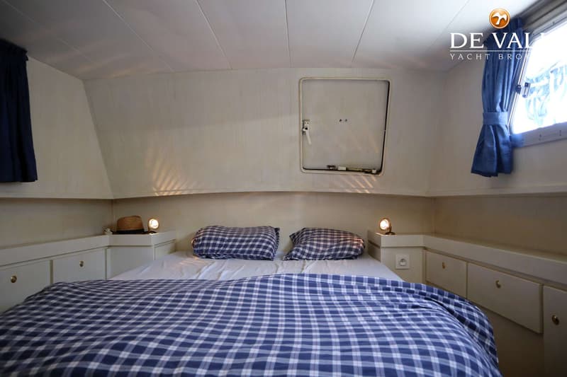 Een kajuit met een tweepersoonsbed met blauw-wit geruit beddengoed, twee kussens en twee nachtlampjes. — TMBoats TMB36eco