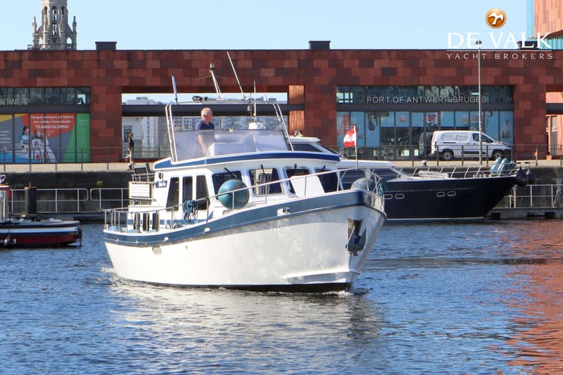 Een witte motorboot met blauwe accenten vaart op het water, met een man aan het roer. — TMBoats TMB36eco