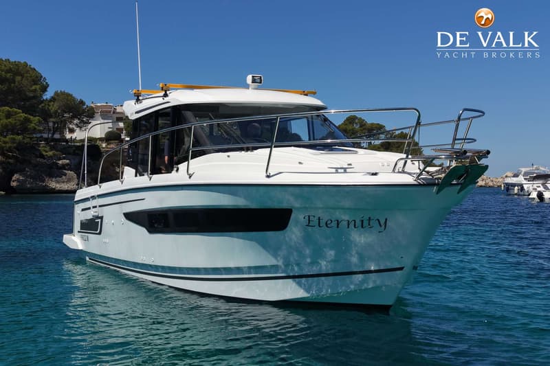 Een witte motorboot met de naam "Eternity" op de boeg ligt in helderblauw water onder een strakblauwe lucht.