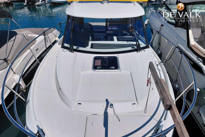 Een witte motorboot met een raam in het voordek en een voorruit, omringd door andere boten in het water.