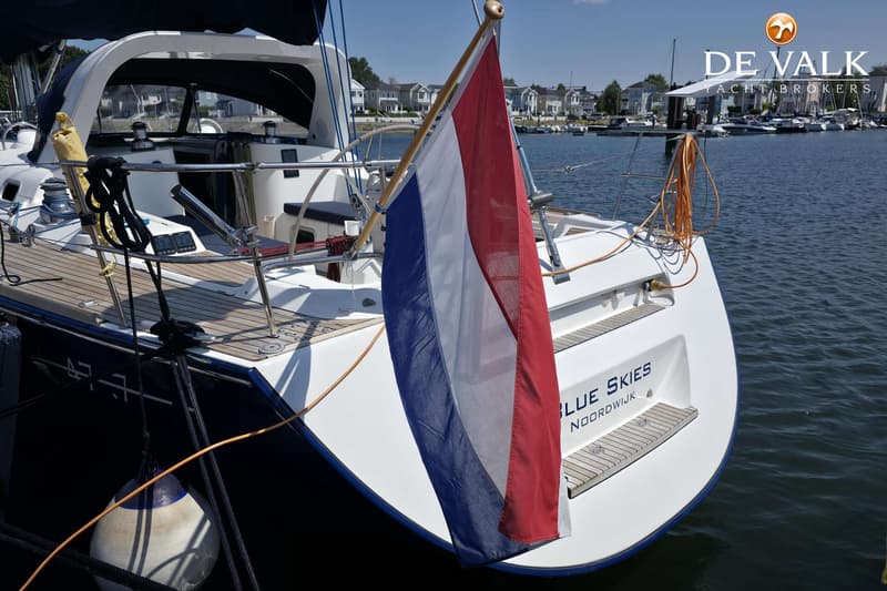 Een boot met een Nederlandse vlag aan de achtersteven, met de naam "BLUE SKIES NOORDWIJK" op de spiegel.