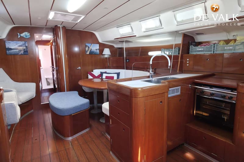De foto toont het interieur van een boot met een kombuis, zithoek en een doorgang naar een toiletruimte.
