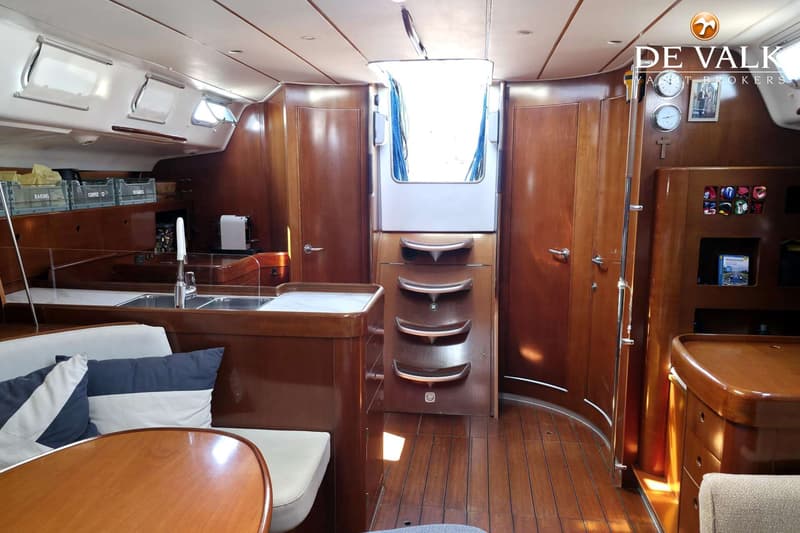 De foto toont het interieur van een boot met een kombuis, zithoek, houten vloer en kajuitingang. — Beneteau First 47.7