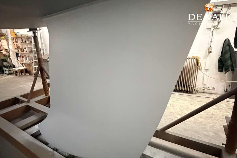 Een witte kiel van een boot staat op een houten bok in een werkplaats. — Beneteau First 47.7
