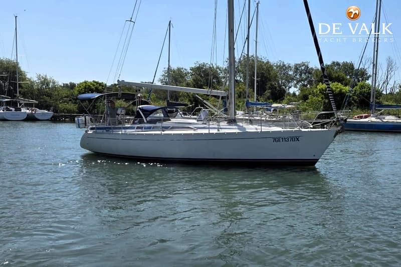 Een witte zeilboot met de registratie "7GE1137DX" ligt in het water, met bomen op de achtergrond. — Grand Soleil 38