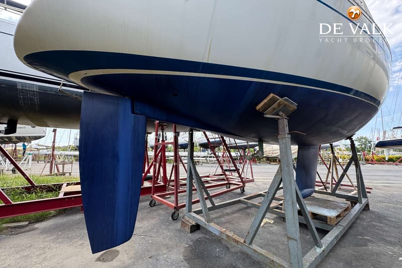Een witte boot met een blauwe streep en een blauwe onderkant staat op bokken op een werf. — Grand Soleil 38