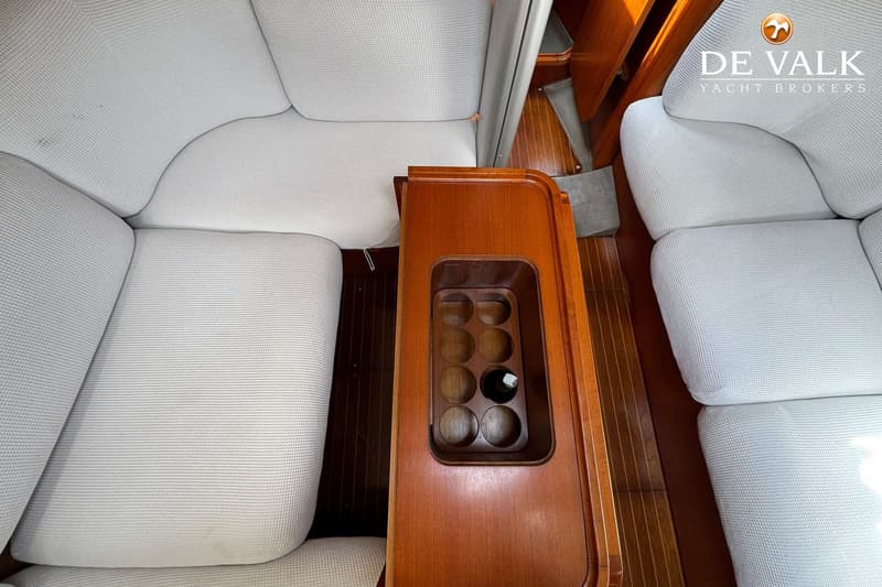 De foto toont een interieur met lichte kussens, een houten tafel met flessenhouder en een fles, en een houten vloer.