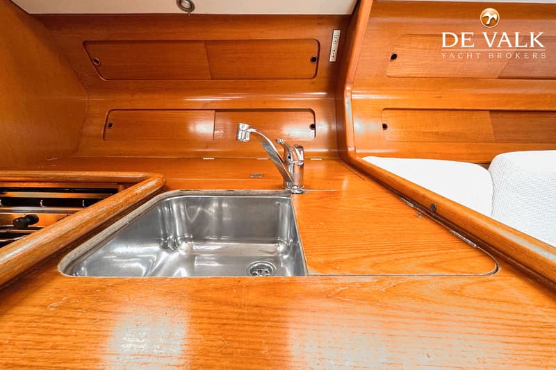 Een detailfoto van een scheepskeuken met een roestvrijstalen spoelbak en een chromen kraan, omringd door houten afwerking.