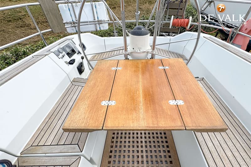 Een houten cockpit tafel met scharnieren is zichtbaar, omringd door een wit dek met teakhouten afwerking.