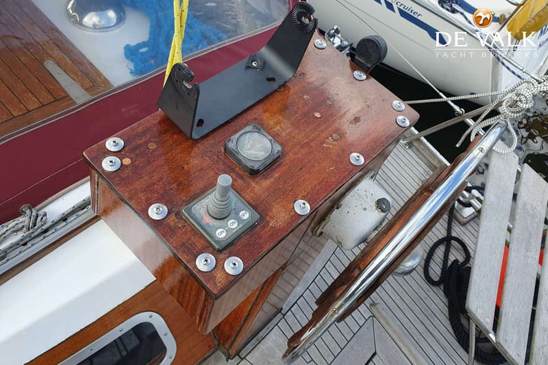 Een houten stuurstand met een joystick voor de boegschroef, een kompas en een zwarte beugel.