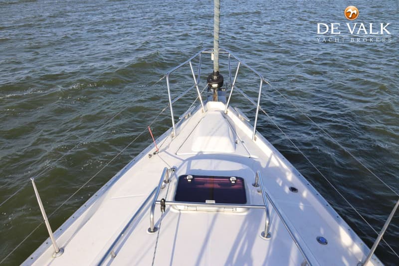 De foto toont de boeg van een witte zeilboot met een mast, reling en een luik, varend op water. — Beneteau Oceanis 411