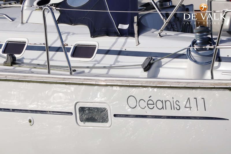 Een witte boot met de naam "Océanis 411" op de zijkant, met ramen en een blauwe hoes op het dek. — Beneteau Oceanis 411