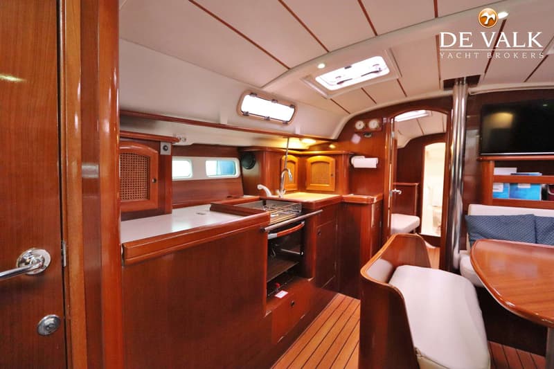 Een interieur van een boot met een kombuis, zithoek en houten afwerking. — Beneteau Oceanis 411