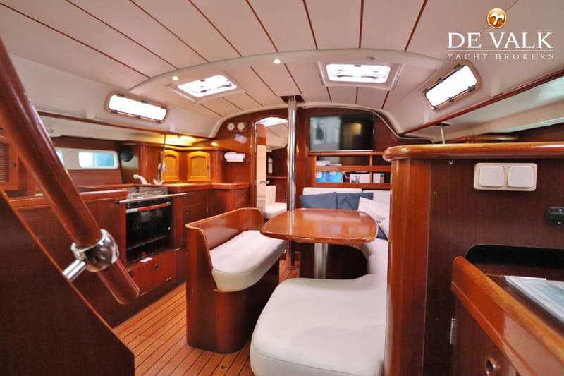 De foto toont het interieur van een boot met een houten afwerking, zithoek, kombuis en een televisie. — Beneteau Oceanis 411
