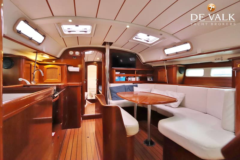 De foto toont het interieur van een boot met een kombuis, salon en een doorgang naar een toiletruimte. — Beneteau Oceanis 411