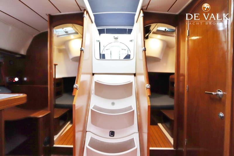 Een interieurfoto van een boot met een trap naar beneden, omringd door houten panelen en een kajuit. — Beneteau Oceanis 411