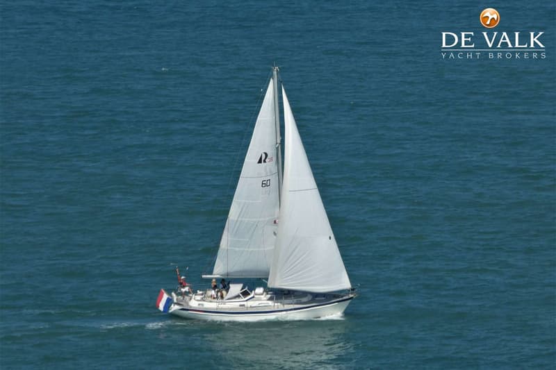 Een witte zeilboot met twee zeilen en een Nederlandse vlag vaart op een blauwe zee. — Hallberg Rassy 39