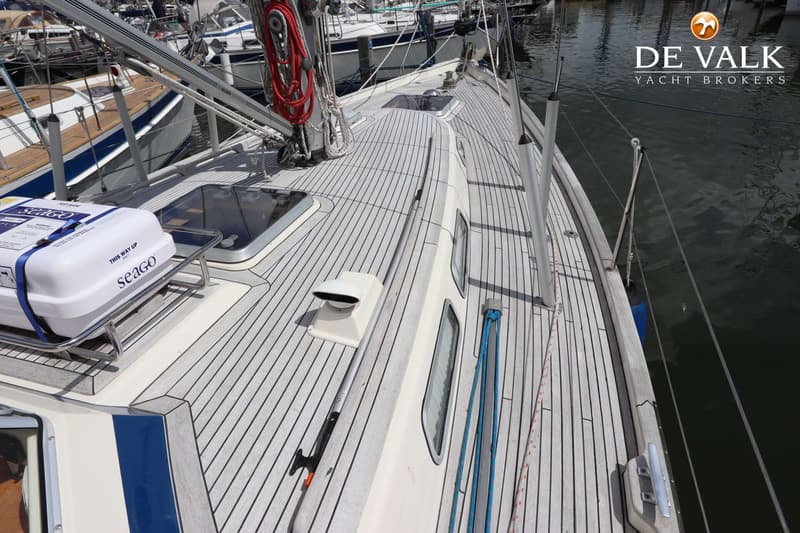 Een bovenaanzicht van het dek van een zeilboot met een reddingsvlot en een mast, liggend in het water. — Hallberg Rassy 39