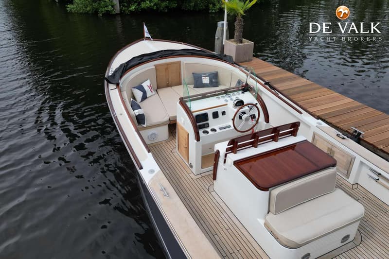 Een bovenaanzicht van een witte boot met houten details, liggend aan een houten steiger. — Oak Brothers 29 Lobster