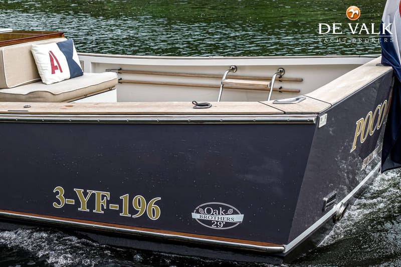 Een donkerblauwe boot met houten accenten en de registratie "3-YF-196" en "Oak Brothers 29'" op de zijkant.