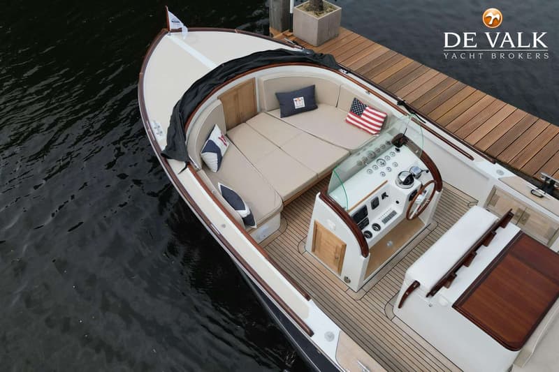 Een bovenaanzicht van een boot met een stuurwiel, beige kussens en een Amerikaanse vlag op een kussen.