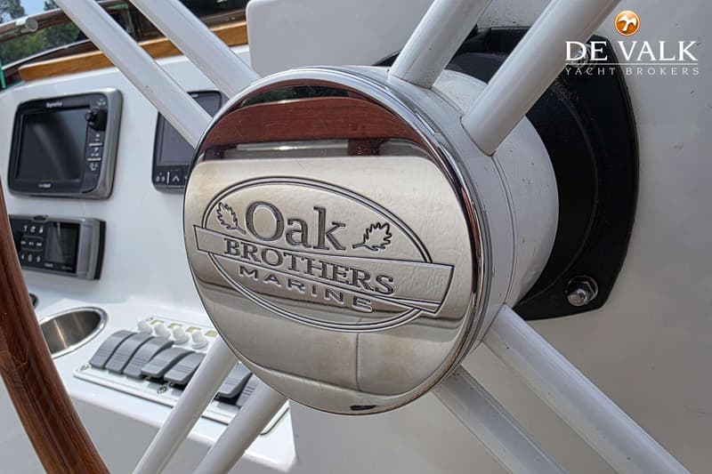 Een close-up van een stuurwiel met in het midden het logo "Oak Brothers Marine", met op de achtergrond navigatieapparatuur.