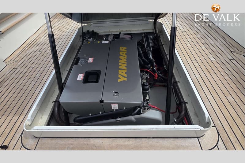 Een Yanmar scheepsmotor is zichtbaar in een open motorruimte, omringd door een houten dek.