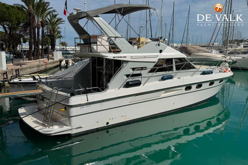 Een witte Fairline motorboot ligt in een haven met palmbomen op de achtergrond en andere boten. — Fairline 43