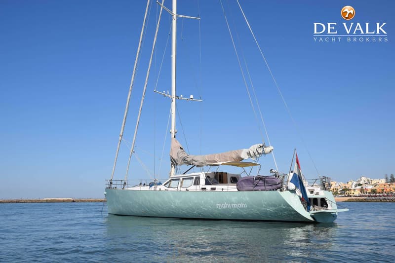 Een lichtgroene zeilboot met de naam "mahi mahi" op de romp ligt in het water onder een helderblauwe lucht. — CRN 63