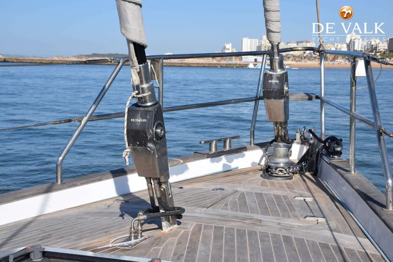 De foto toont het teakdek aan de boeg van een zeilboot met twee Reckmann rolreefsystemen, een ankerlier en bolders. — CRN 63