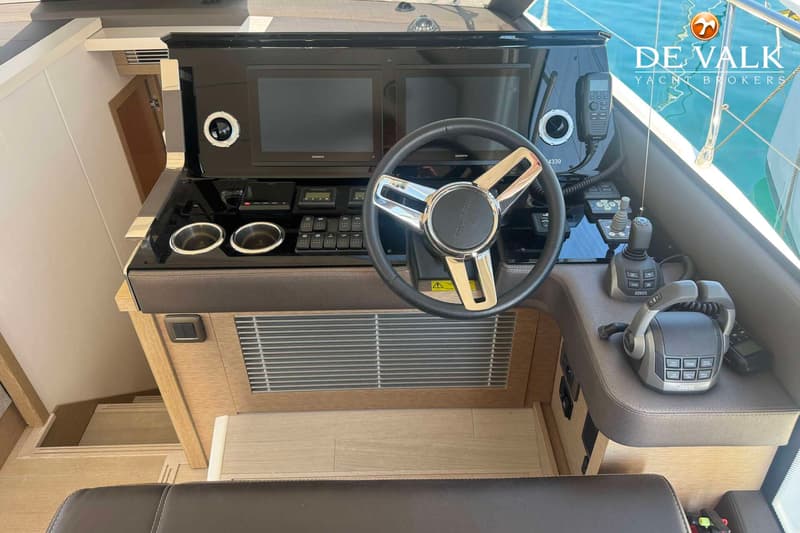 De foto toont het stuur en het dashboard van een boot met twee Garmin schermen, een marifoon, schakelaars en…