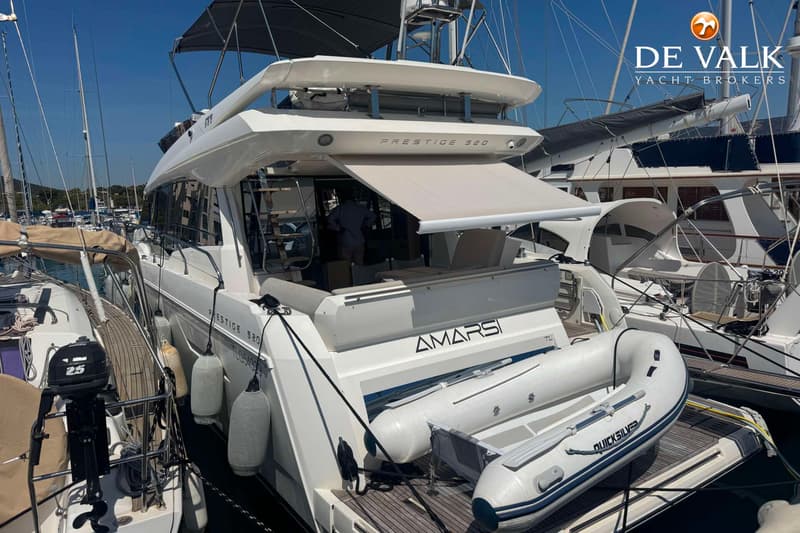 Een witte motorboot met de naam "AMARSI" en "PRESTIGE 520" is afgemeerd, met een bijboot achterop. — Jeanneau Prestige 50.