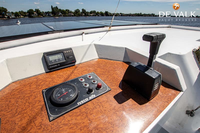 Een close-up van een bootstuurstand met een motorbediening, een toerenteller en een dieptemeter, met op de achtergrond…