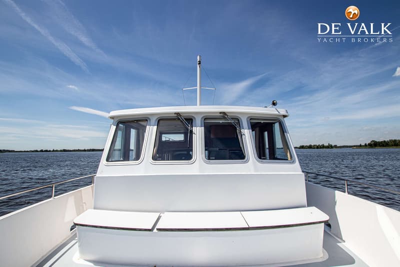Een witte boot met een stuurhut en een mast, varend op een meer onder een blauwe hemel met wolken. — Treffer Offshore 14,95