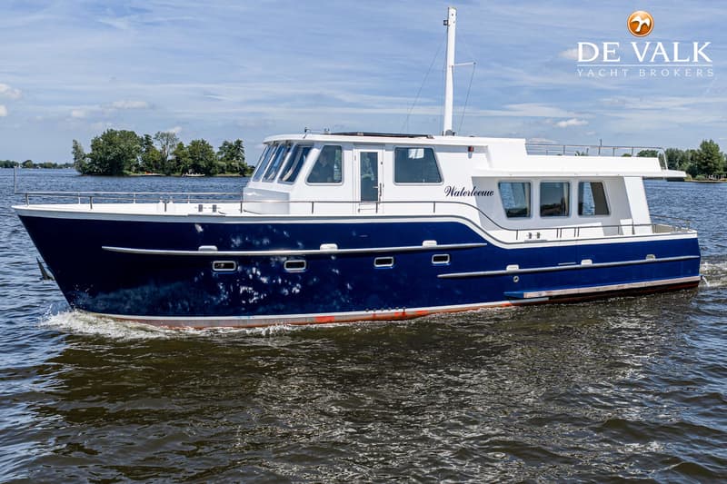 Een blauw-witte motorboot met de naam "Waterleeuw" vaart op een waterweg met bomen op de achtergrond.