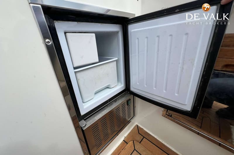 Een openstaande koelkast met een klein vriesvak en twee witte bakken erin, ingebouwd in een boot. — Long Island 40 Runabout