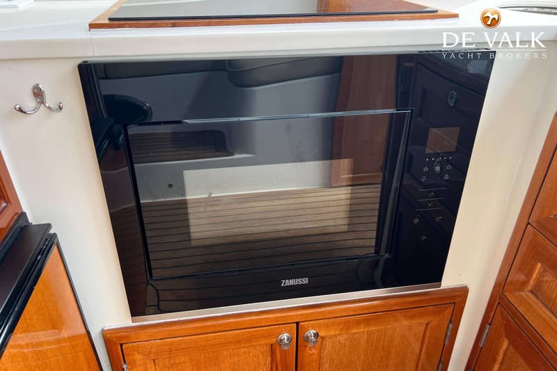 Een ingebouwde zwarte Zanussi magnetron met bedieningspaneel, omringd door houten kasten en een wit aanrechtblad.