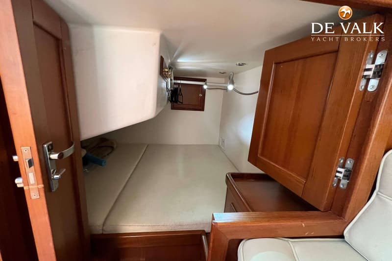 Een kajuit met een bed, houten kasten, een deur en een leeslampje. — Long Island 40 Runabout