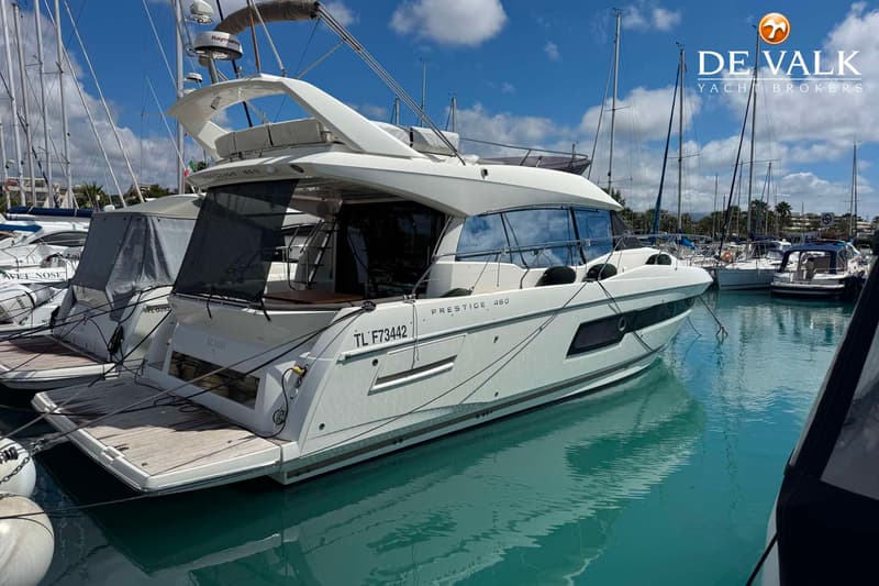 Een witte motorboot met de naam "PRESTIGE 460" en registratienummer "TL F73442" ligt aangemeerd in een haven.