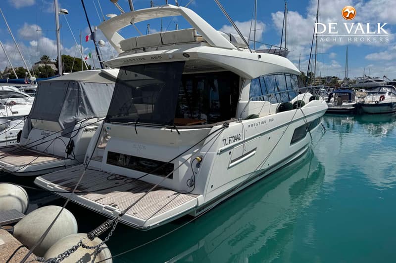 Een witte motorboot met de naam "PRESTIGE 460" en "EL NIDO TL" ligt afgemeerd in een haven. — Jeanneau Prestige 460