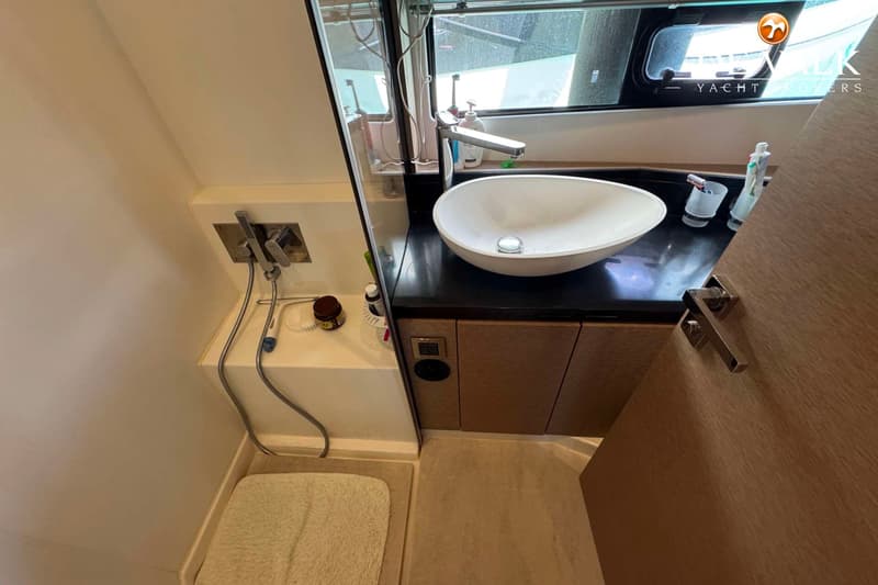 Een badkamer met een wastafel, spiegel, douche en een raam met uitzicht naar buiten.
