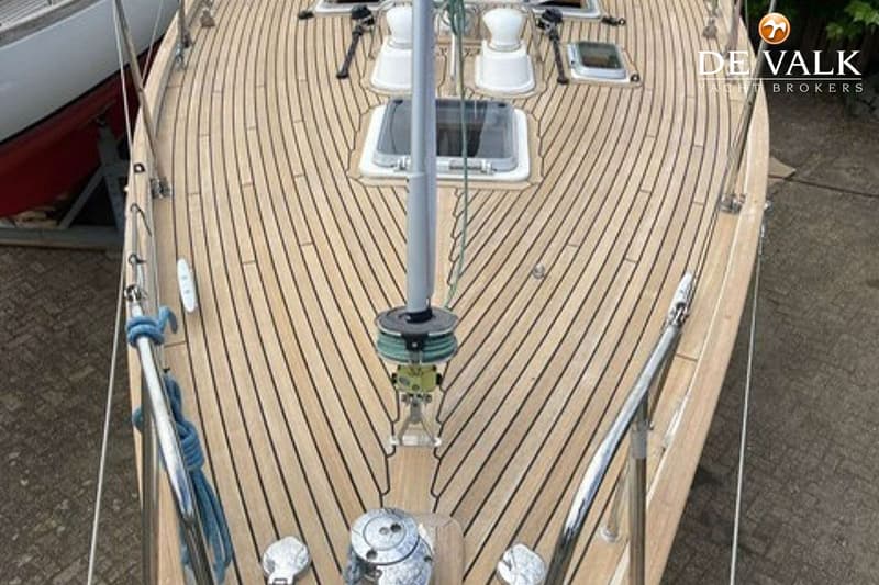 Een bovenaanzicht van het teakhouten dek van een zeilboot met een mast en diverse luiken. — Tradewind 35