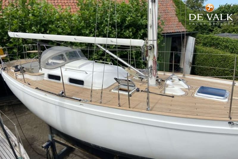 Een witte zeilboot met een teakhouten dek staat op de wal, met een mast en giek zichtbaar. — Tradewind 35